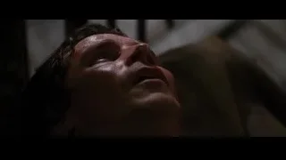 Man with closed eyes and bloody face in dimly lit room — Batman: The Dark Knight Rises