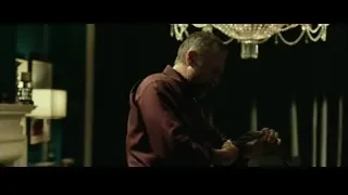 Man in maroon shirt in dimly lit room — John Wick