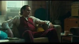 Man in red suit sitting on couch deep in thought — Joker