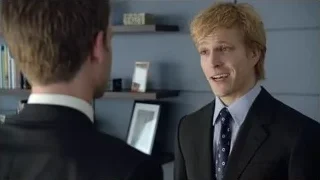 Two men in suits in room with bookshelves — Suits