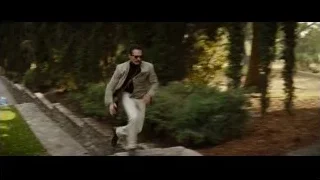 man in beige suit pushing plant — Ford v Ferrari