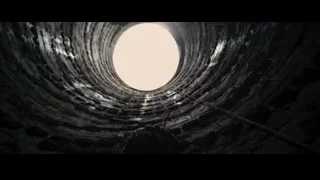 Person in hooded cloak in stone tunnel — Batman: The Dark Knight Rises