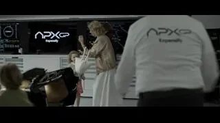People around F1 car with Expensify screen — F1