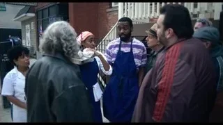 man in apron holding food talking to woman — The Bear