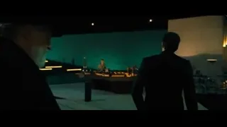 Two men in dimly lit room with large screen — John Wick: Chapter 4