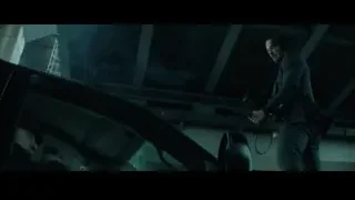 Man in suit holding gun looking out car window — John Wick