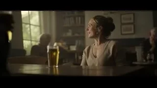 Woman sitting at table with beer in dim room — F1