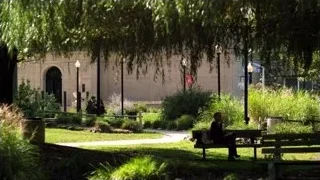 People in park with stone building — Suits