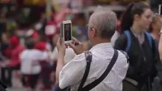 Elderly man taking photo on busy street — Screened Out