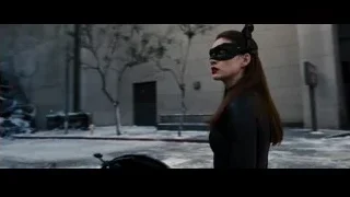Woman crouching by pile of cars — Batman: The Dark Knight Rises