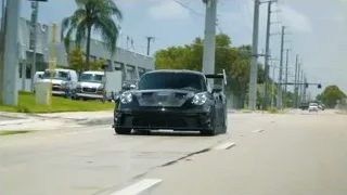 black sports car driving on palm tree street — Sports Cars
