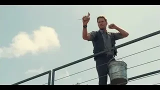 Man on metal railing with arms raised — Jurassic World