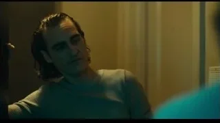 man in light blue sweater in dimly lit room — Joker