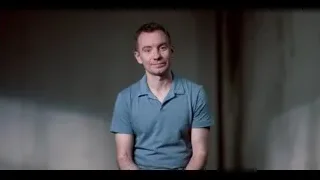 man in blue polo shirt in dim room — The Social Dilemma
