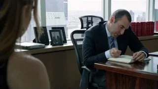 man writing at office desk with woman — Suits