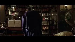 person in robe by bookshelf and piano — Batman