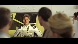 man speaking in front of large screen — F1