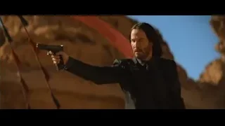 man with gun in desert with flags — John Wick: Chapter 4