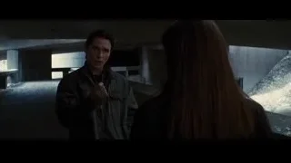 man pointing gun at woman in concrete room — Batman: The Dark Knight Rises