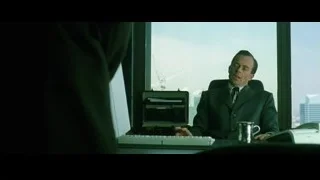 Man in suit at desk with city view — The Matrix