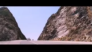 White car driving on winding cliffside road — Iron Man