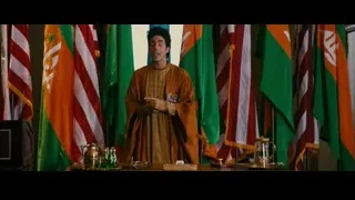 man giving speech behind podium with flags — The Dictator