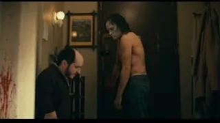 shirtless man covered in blood in dimly lit room — Joker