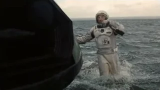 man in space suit walking on ocean — Interstellar