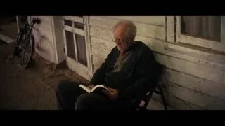 Elderly man reading book in front of house — Interstellar